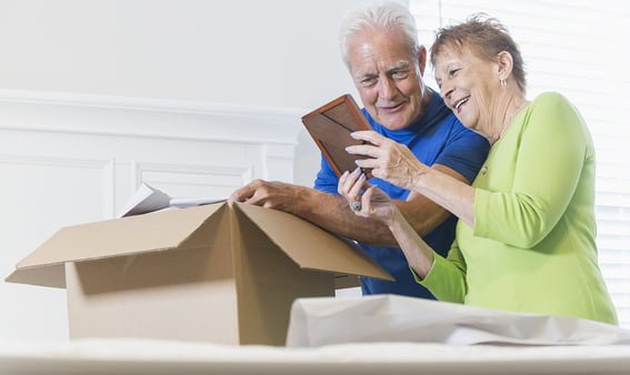 Senior couple packing box, looking at picture frame