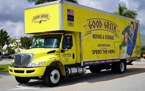 Camión amarillo de Good Greek Moving &amp; Storage con Spero el Superhéroe de camino a una mudanza en Florida.